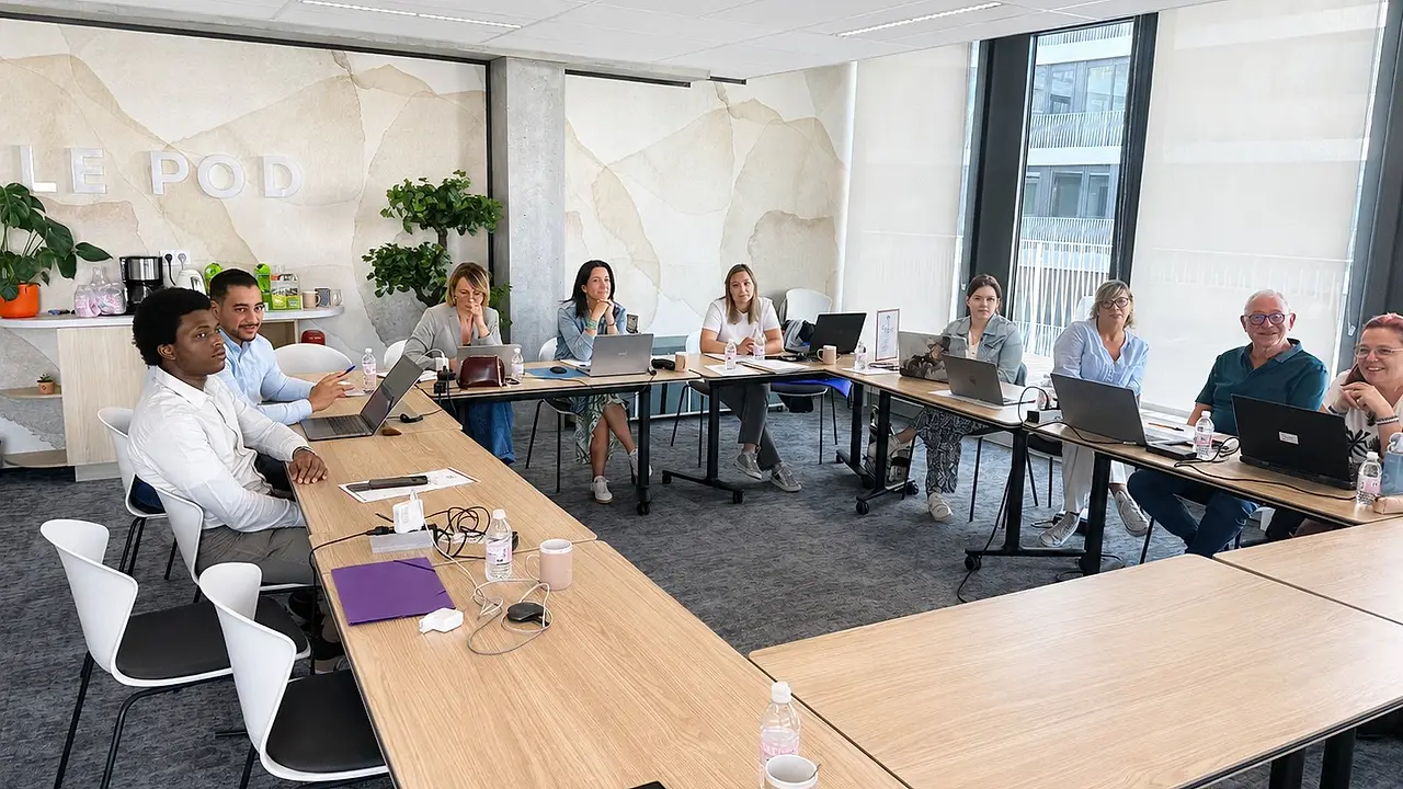 Groupe de participants devant leurs ordinateurs portables, pendant une session de formation en salle.