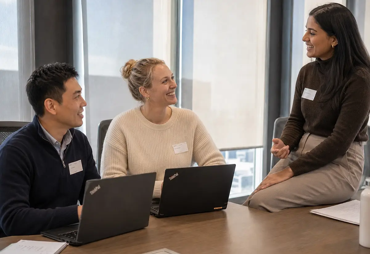 Trois personnes en discussion autour de leurs ordinateurs portables