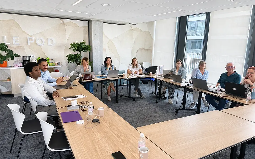 Des participants suivent une session de formation devant leur ordinateur portable, en salle