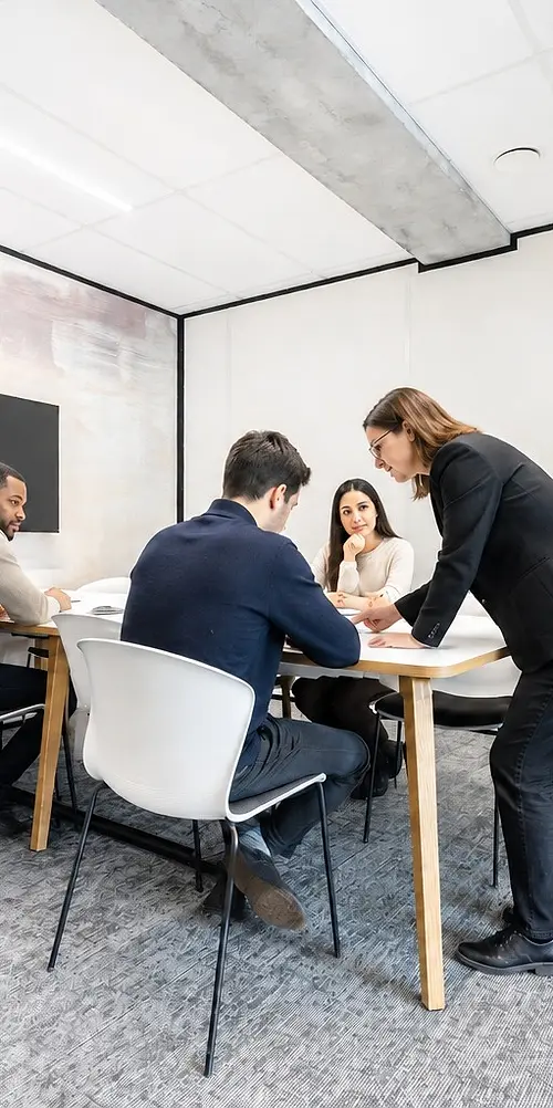 Une formatrice accompagne trois participants penchés sur un document